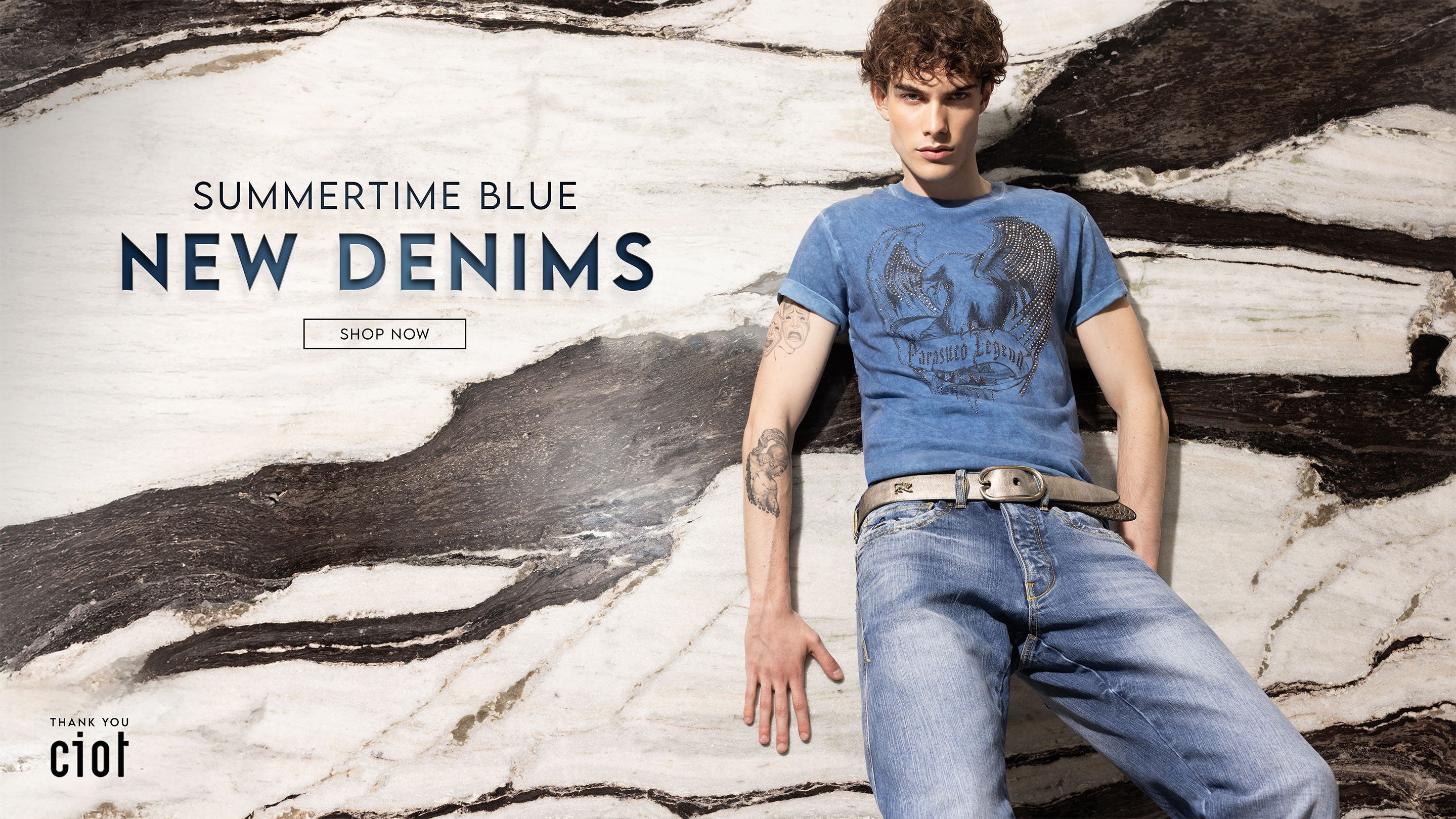 Attractive man wearing a blue archival top from the 1990s and light wash denim jeans.